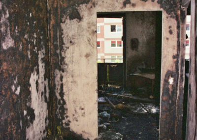 Ein Verbrannter Flur mit Gegenstände und abgelöster Tapete an Decken und Wänden